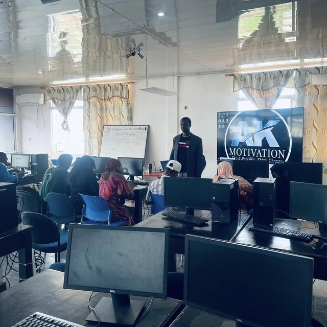 Abdulai training a group in a computer lab with the AK Motivation logo on screen